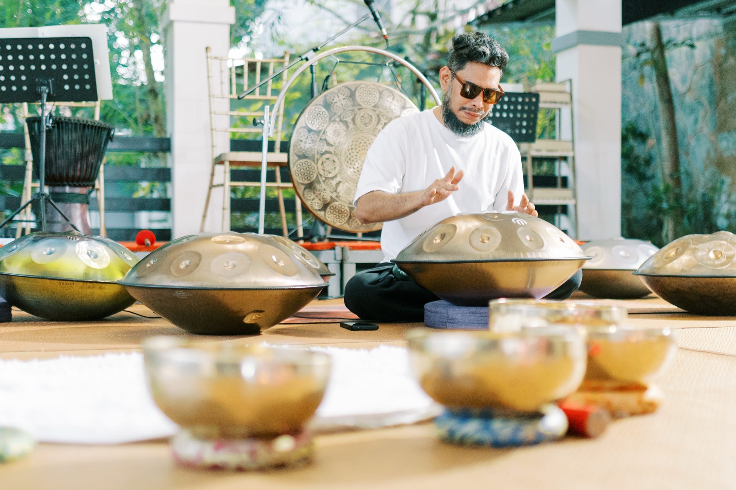A musician playing handpans surrounded by singing bowls during a sound healing session