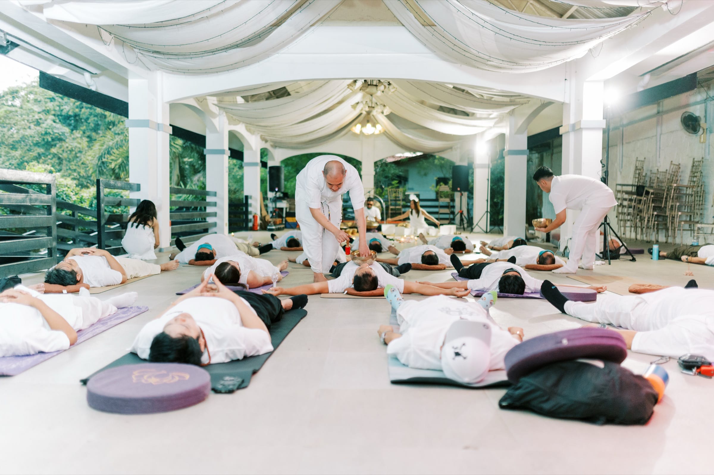Participants lying down in a guided sound bath beneath flowing white drapery