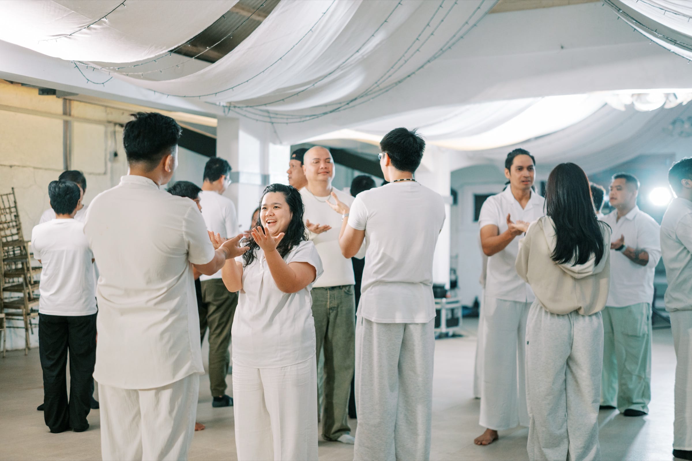 A circle of participants in white, clapping and connecting in an integration circle