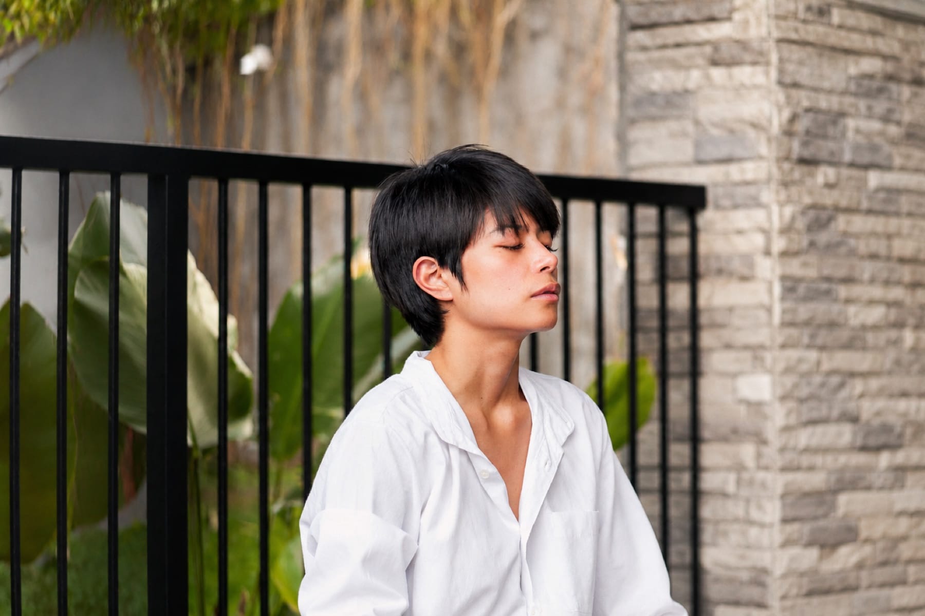 A participant sitting outdoors with eyes closed, breathing in a quiet moment of stillness