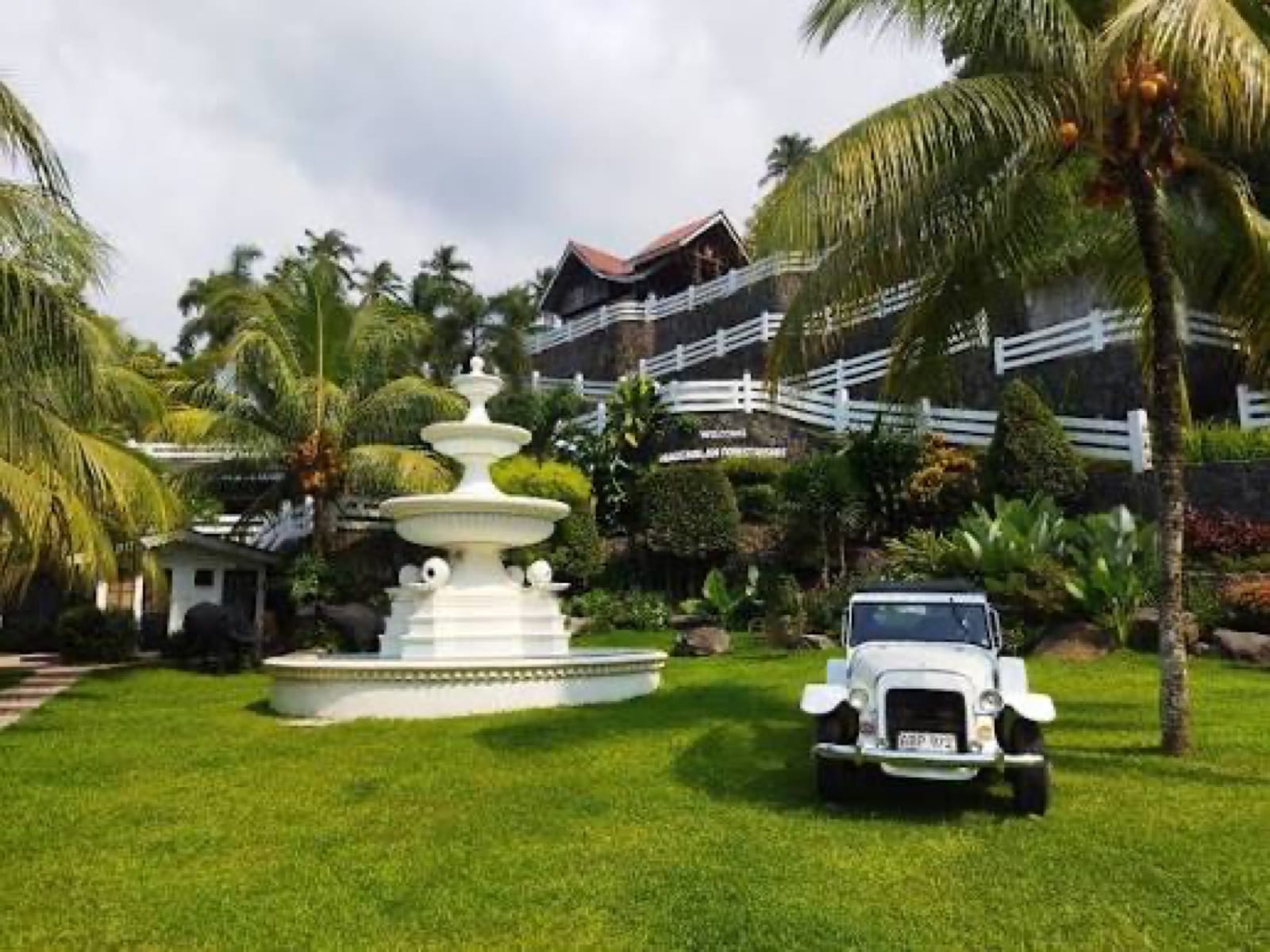 The entrance to Nagcarlan Forest Resort, with a white fountain and tropical gardens