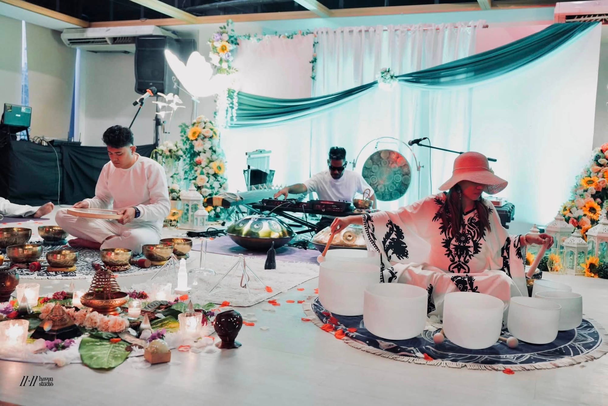 A sound and cacao ceremony in progress with crystal bowls, gongs, and floral arrangements
